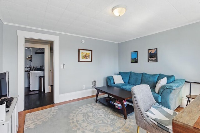 living room featuring crown molding, baseboards, and wood finished floors