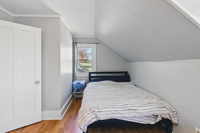 bedroom with baseboards, vaulted ceiling, and wood finished floors