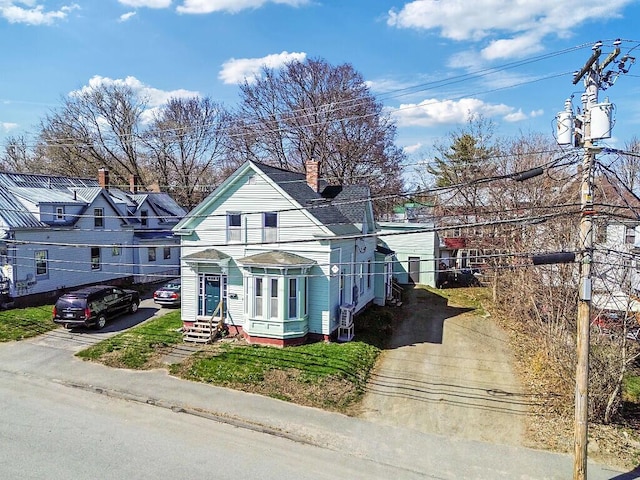 victorian home with a shingled roof, a chimney, and driveway