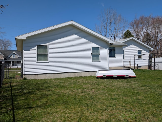 rear view of property featuring fence and a lawn