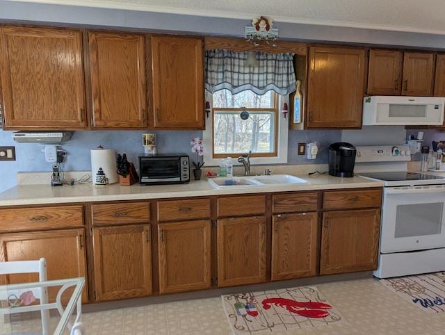 kitchen featuring a sink, brown cabinets, white appliances, and light floors