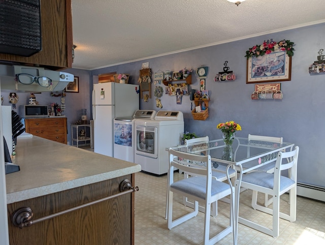 kitchen featuring ornamental molding, freestanding refrigerator, stainless steel microwave, light floors, and washing machine and dryer