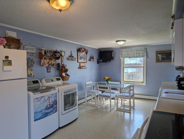 kitchen with baseboard heating, a sink, a textured ceiling, freestanding refrigerator, and washing machine and dryer