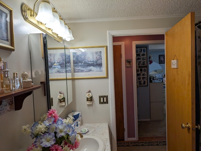 bathroom featuring a textured ceiling, ornamental molding, and vanity