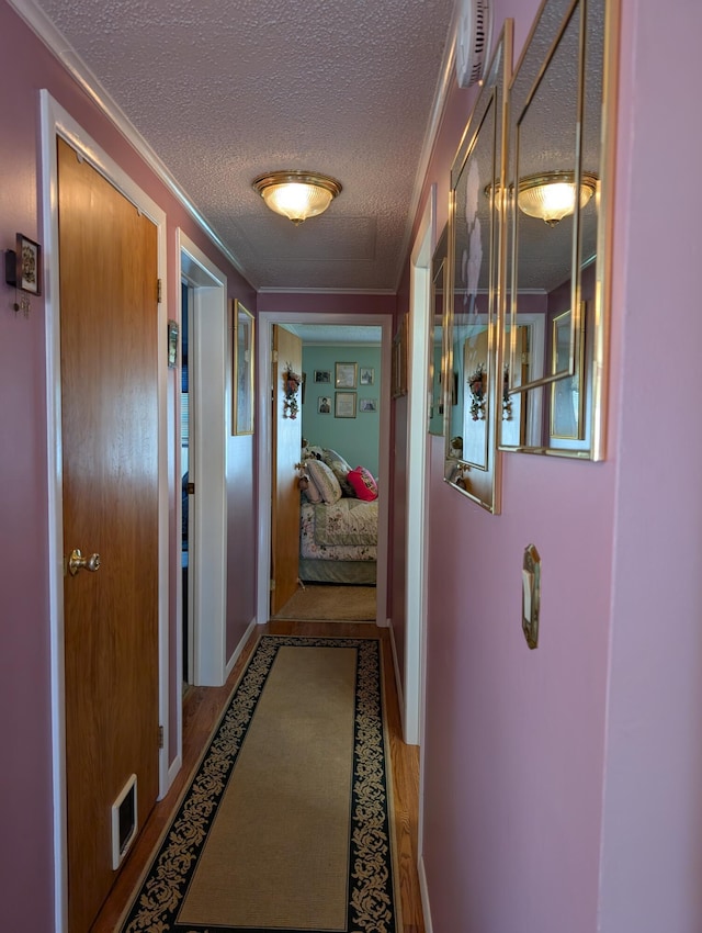 hall featuring crown molding, a textured ceiling, and visible vents