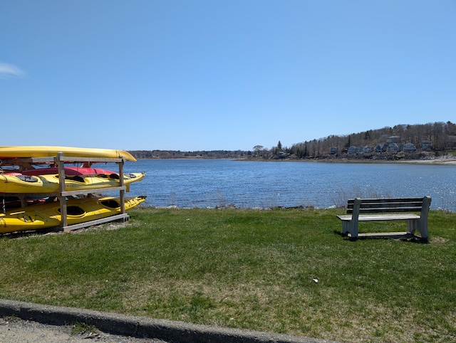view of dock with a lawn and a water view