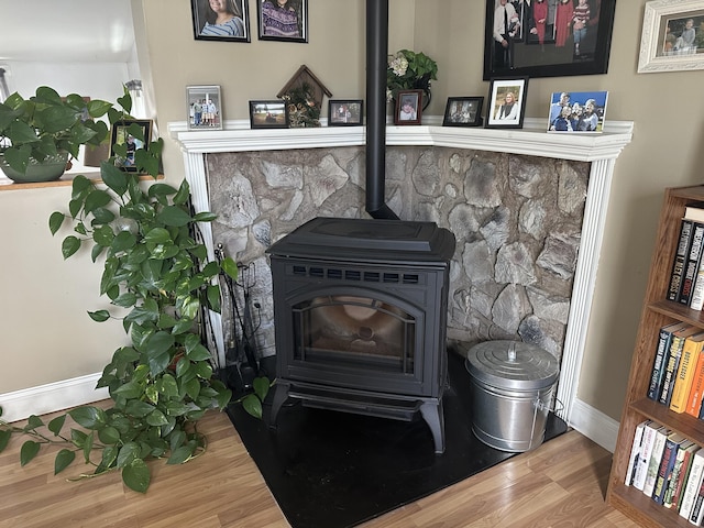 details with baseboards, wood finished floors, and a wood stove