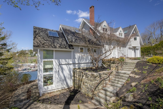 back of property with a chimney and stairway