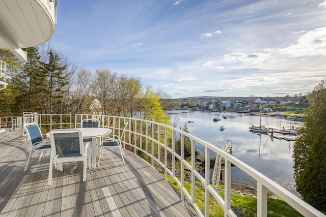 wooden deck with a water view and outdoor dining space