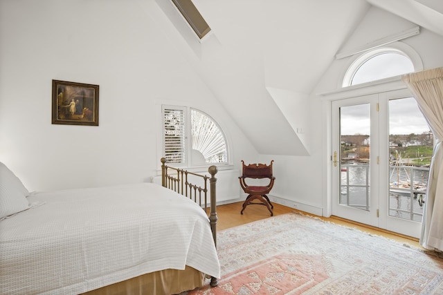 bedroom with high vaulted ceiling, access to exterior, wood finished floors, and multiple windows