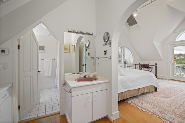 bedroom featuring arched walkways, a sink, vaulted ceiling, and multiple windows