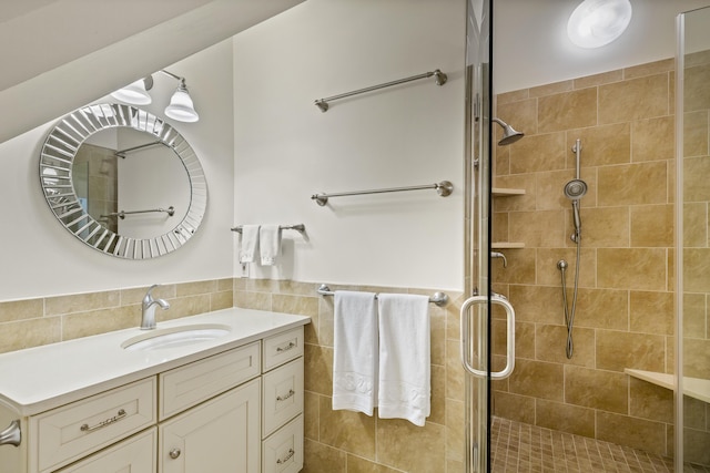 full bathroom featuring vanity, tile walls, a wainscoted wall, and a stall shower