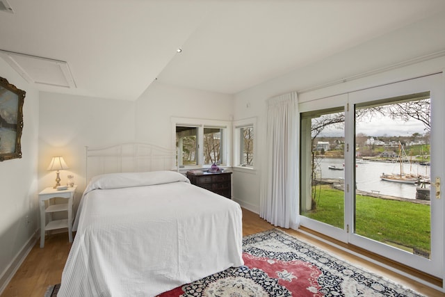 bedroom featuring a water view, access to outside, baseboards, and wood finished floors