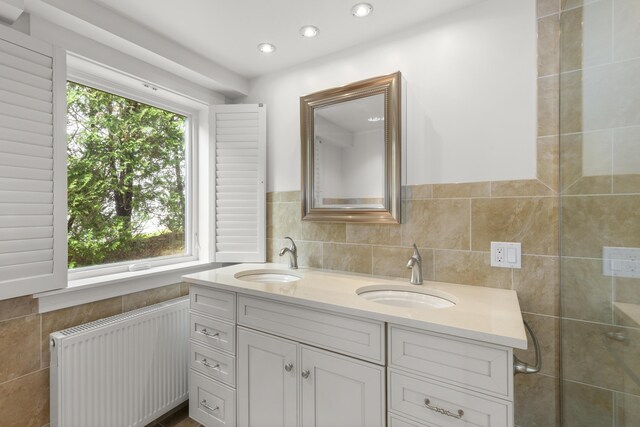 bathroom featuring a sink, radiator, recessed lighting, and double vanity