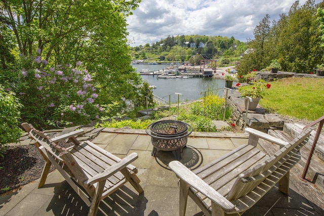 view of patio / terrace featuring a water view, a dock, and a fire pit