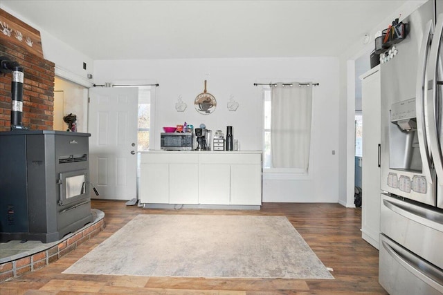 84 Main St, Dixfield, ME 04224 - kitchen featuring stainless steel refrigerator with ice dispenser, a wood stove, and wood finished floors