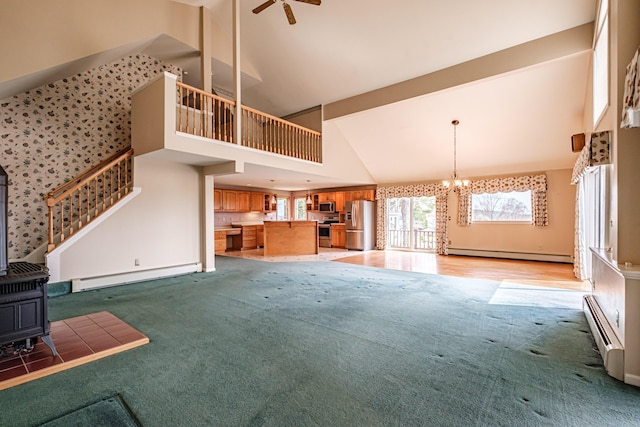 unfurnished living room featuring a wood stove, light carpet, baseboard heating, high vaulted ceiling, and a baseboard heating unit