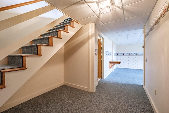 interior space with baseboards, carpet, and a paneled ceiling