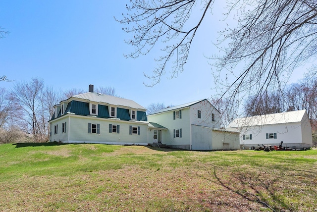 back of property featuring a yard, a gambrel roof, metal roof, and a chimney