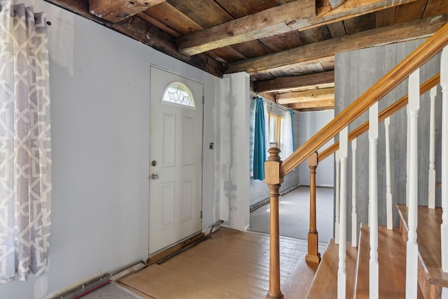 foyer entrance featuring stairs, beamed ceiling, wood ceiling, and light wood-style flooring