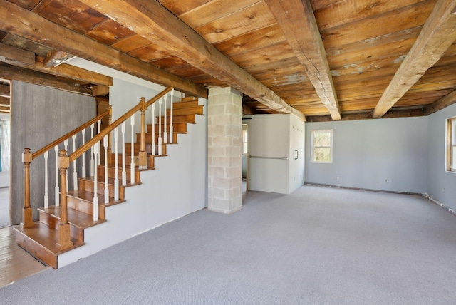 unfurnished living room with beam ceiling, carpet, wood ceiling, and stairway