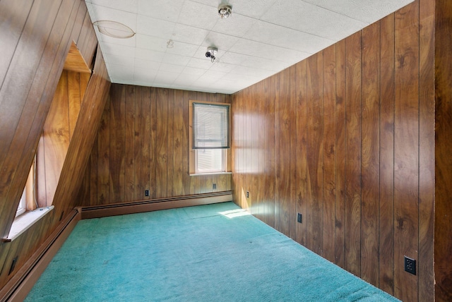 unfurnished room with wooden walls, carpet, and a baseboard heating unit