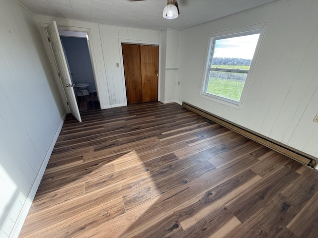 94 Dexter Rd, Corinna, ME 04928 - unfurnished bedroom featuring wood walls, dark wood finished floors, baseboards, a closet, and a baseboard heating unit