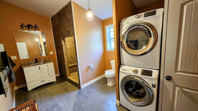 laundry room featuring baseboards, laundry area, and stacked washer / dryer