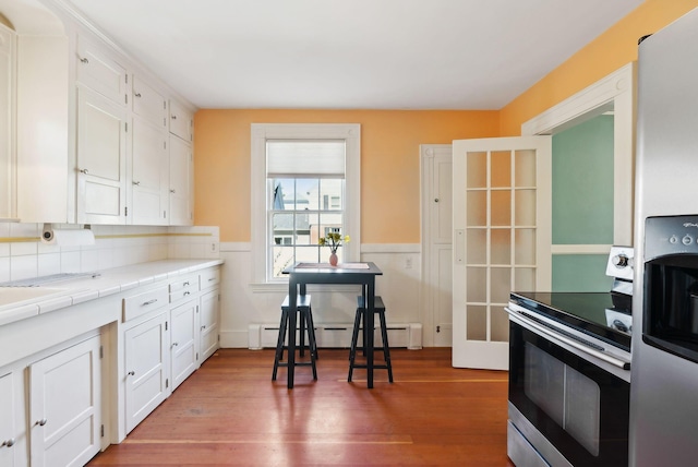 382 College St, Lewiston, ME 04240 - kitchen with appliances with stainless steel finishes, wainscoting, tile counters, white cabinetry, and a baseboard heating unit