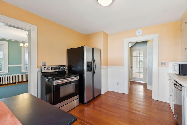 382 College St, Lewiston, ME 04240 - kitchen featuring wainscoting, wood finished floors, radiator heating unit, appliances with stainless steel finishes, and a notable chandelier