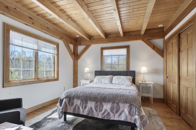 bedroom featuring baseboards, beamed ceiling, wood ceiling, and light wood-style floors