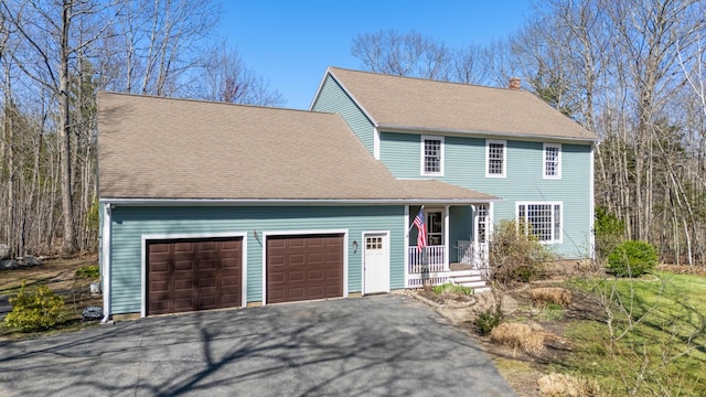 colonial home with driveway, a chimney, and a garage