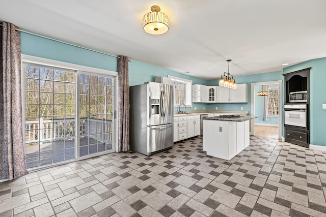 kitchen featuring a center island, open shelves, a sink, stainless steel appliances, and white cabinetry