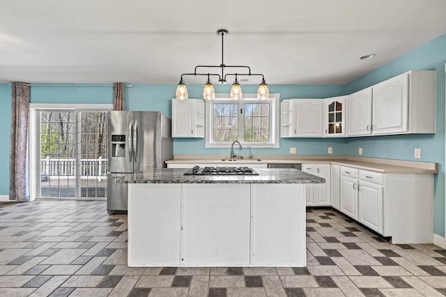 kitchen featuring a sink, stainless steel appliances, decorative light fixtures, white cabinetry, and a kitchen island