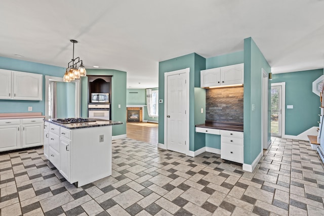 kitchen featuring baseboards, a center island, stainless steel appliances, and white cabinetry