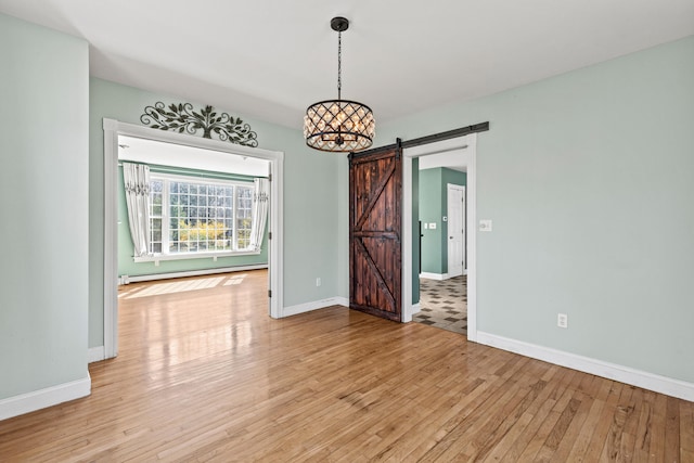 unfurnished dining area featuring baseboards, a baseboard heating unit, a barn door, and light wood-style floors