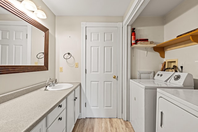 laundry room with separate washer and dryer, a sink, and light wood-style flooring