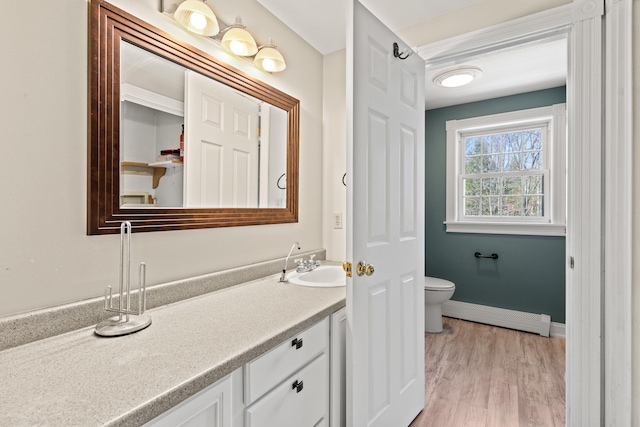 bathroom with vanity, wood finished floors, toilet, baseboards, and baseboard heating