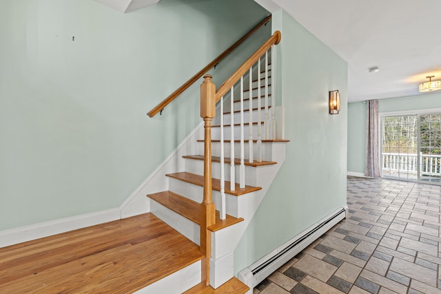 staircase featuring baseboards, stone finish floor, and a baseboard heating unit
