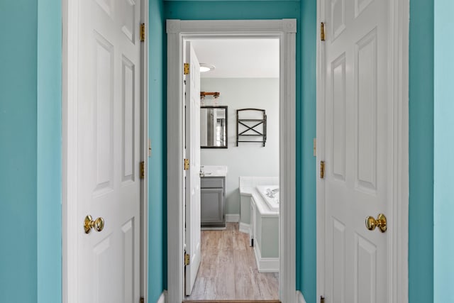 corridor with baseboards and light wood-type flooring