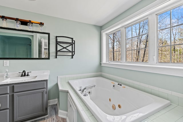 bathroom with a healthy amount of sunlight, vanity, baseboards, and a whirlpool tub