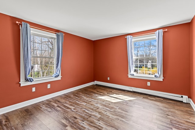 unfurnished room with baseboards, wood finished floors, and baseboard heating