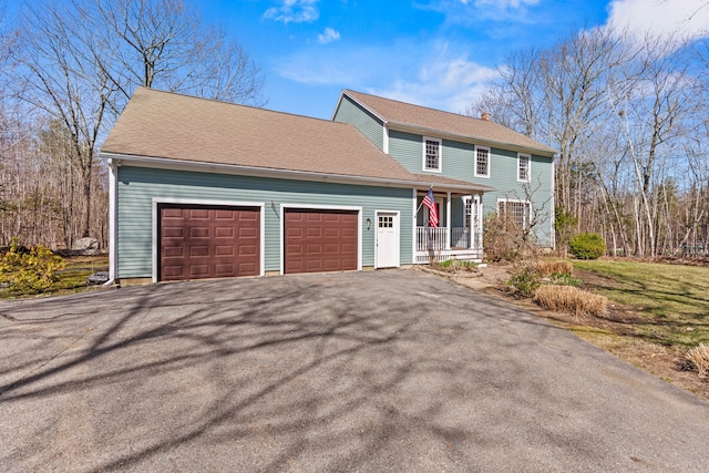 view of front of house with a porch, an attached garage, driveway, and a chimney