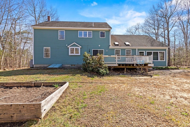 rear view of property featuring a wooden deck, a yard, and a chimney