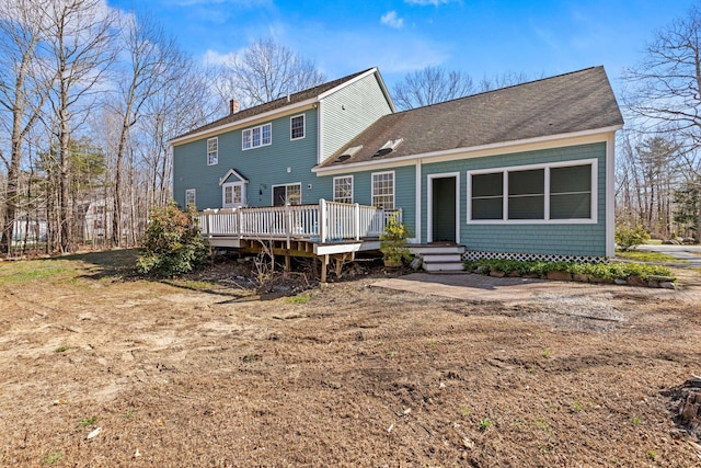 back of house with roof with shingles, a wooden deck, and a chimney