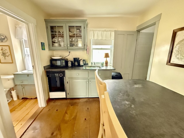 7 Mountain St, Vinalhaven, ME 04863 - kitchen featuring black dishwasher, wood finished floors, glass insert cabinets, and a sink