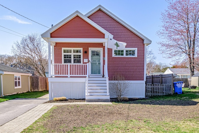bungalow-style house with fence, covered porch, and a front lawn