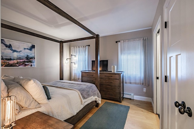 bedroom with light wood-type flooring, a baseboard radiator, and baseboards