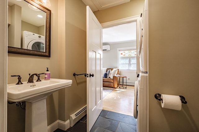 bathroom featuring baseboards, baseboard heating, an AC wall unit, and stacked washer and clothes dryer