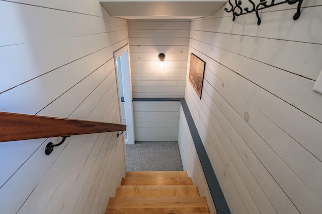 stairway featuring wood walls and carpet flooring